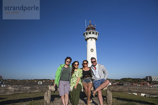 Eine Gruppe von Freunden mit einem Leuchtturm im Hintergrund außerhalb des Zentrums von Amsterdam; Egmond aan Zee  Holland'.