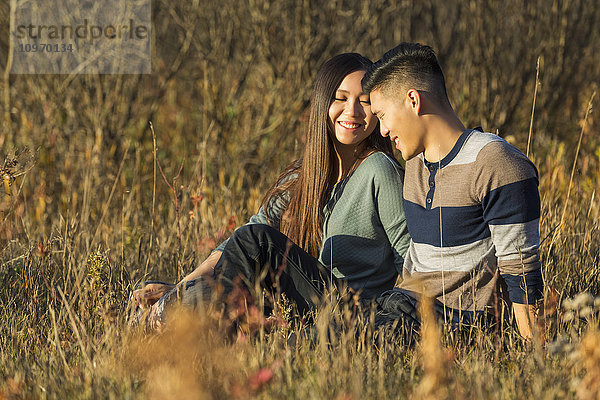 Ein junges asiatisches Paar genießt die gemeinsame Zeit im Freien in einem Park im Herbst in der Wärme des Sonnenlichts am frühen Abend; Edmonton  Alberta  Kanada'.