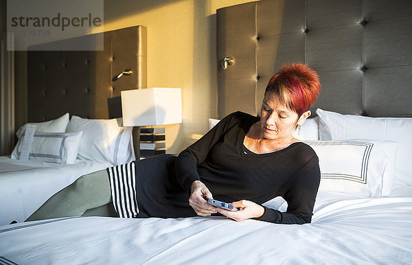 Eine Frau liegt auf einem Hotelbett und schreibt eine SMS; Vancouver  British Columbia  Kanada .