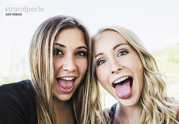 Zwei Freundinnen posieren für die Kamera und machen lustige Grimassen in einem Stadtpark in der Innenstadt; Edmonton  Alberta  Kanada'.