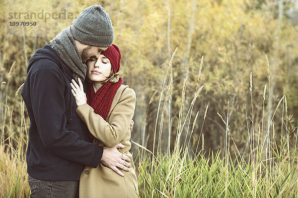 Ein junges Paar  das sich im Herbst in einem Stadtpark eng umarmt; Edmonton  Alberta  Kanada