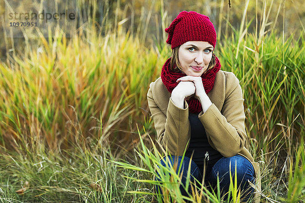 Eine junge Frau posiert für die Kamera und schaut schüchtern während eines Ausflugs in einem Stadtpark im Herbst; Edmonton  Alberta  Kanada'.