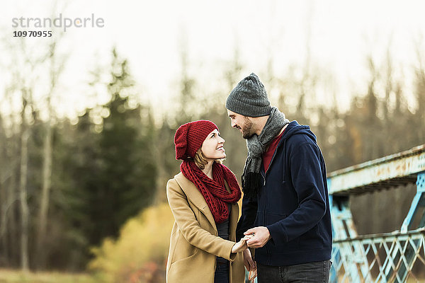 Ein junges Paar  das sich auf einer Brücke in einem Park im Herbst in die Augen schaut und die Hände hält; Edmonton  Alberta  Kanada'.