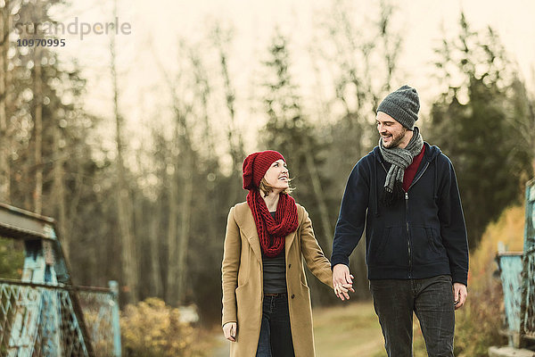 Ein junges Paar  das im Herbst auf einer Brücke in einem Stadtpark spazieren geht; Edmonton  Alberta  Kanada'.