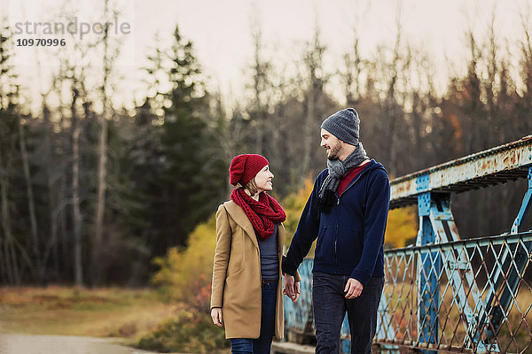 Ein junges Paar geht im Herbst auf einer Brücke in einem Stadtpark spazieren; Edmonton  Alberta  Kanada'.
