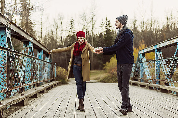 Ein junges Paar  das auf einer Brücke in einem Stadtpark im Herbst zu tanzen vorgibt; Edmonton  Alberta  Kanada'.