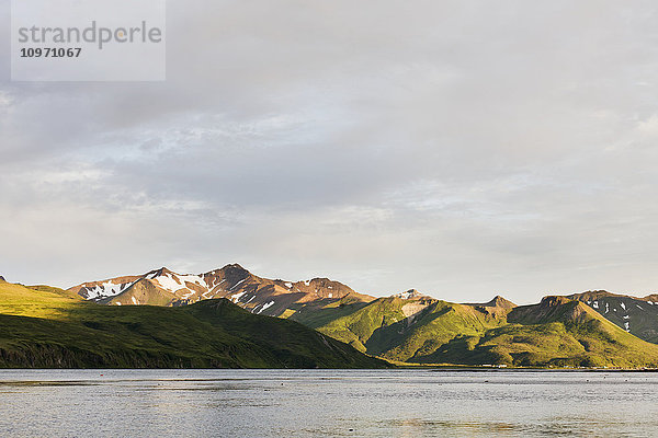Berge und eine Stadt entlang der Küstenlinie auf Unimak Island; False Pass  Alaska  Vereinigte Staaten von Amerika'.