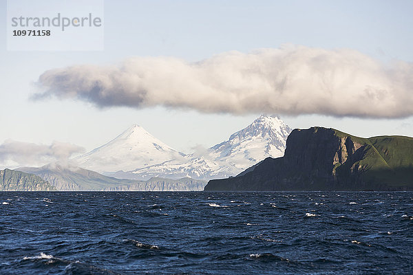 Shishaldin-Vulkan und Isanotski-Gipfel im Hintergrund der zerklüfteten Felsküste von Cape Pankof auf der Insel Unimak  östliche Aleuten; Südwest-Alaska  Vereinigte Staaten von Amerika'.