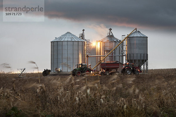 Getreidesilos und Traktor unter einem dramatischen Himmel bei Sonnenuntergang; Quebec  Kanada