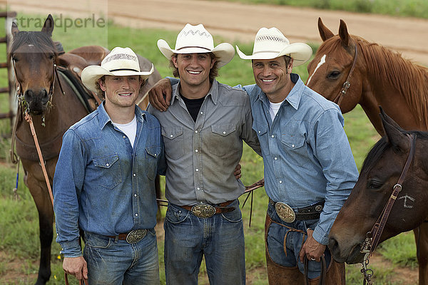Landwirtschaft - Drei lächelnde Cowboys posieren mit ihren Pferden nach einem Arbeitstag / Childress  Texas  USA.