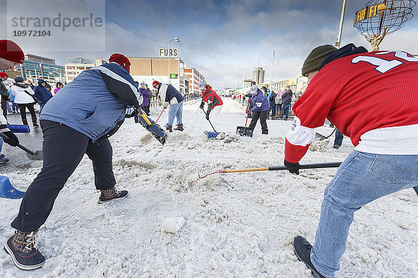 Freiwillige schaufeln an einer Straßenkreuzung auf der 4th Avenue während des feierlichen Starttages des Iditarod 2015 in Anchorage  Alaska  Schnee auf die Strecke zurück