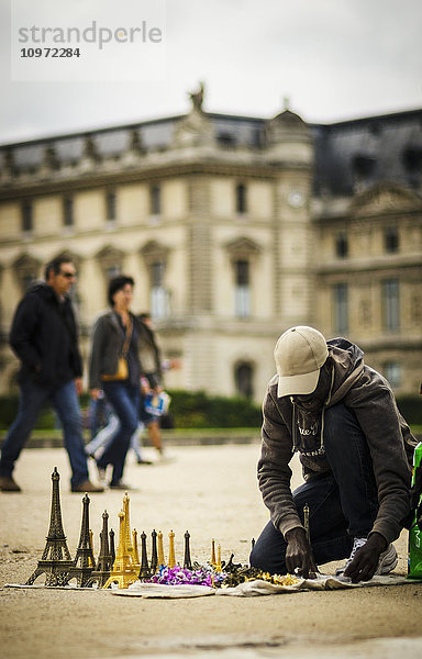 Mann bereitet sich darauf vor  vor dem Louvre Eiffelturm-Miniaturen an Touristen zu verkaufen; Paris  Frankreich'.