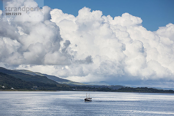 Wogende Wolken und ein Boot im Meer vor der Küste; Isle of Mull  Argyll und Bute  Schottland