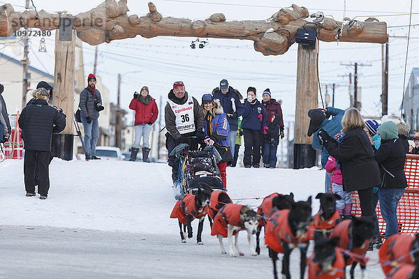 Ken Anderson und seine Frau verlassen die Zielrutsche in Nome nach seiner Ankunft beim Iditarod 2015