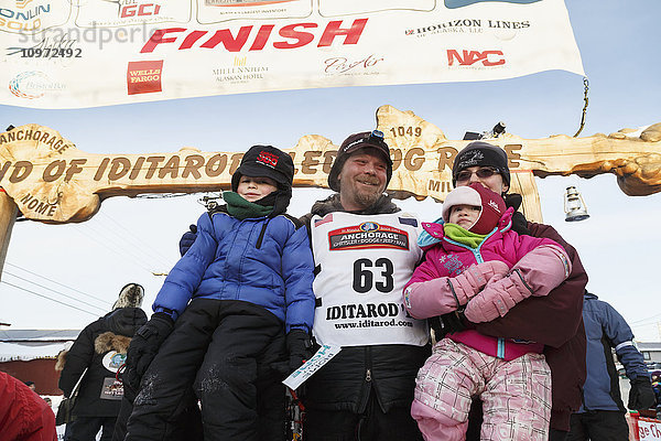 Aaron Burmeister posiert mit seiner Familie kurz nach seinem dritten Platz beim Iditarod 2015 in Nome