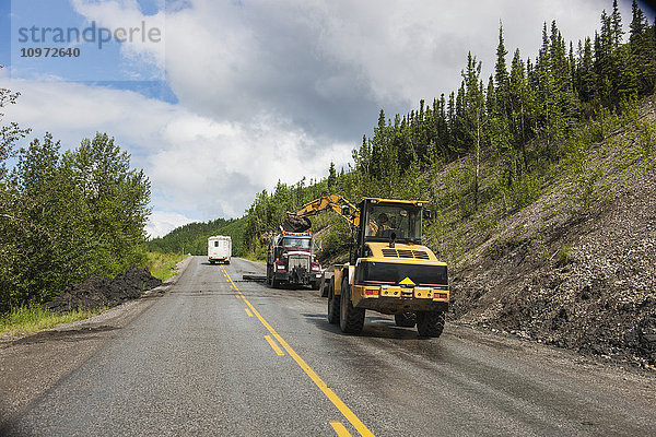 Ein Wohnmobil fährt an einem Straßenbautrupp vorbei  der auf dem Alaska Highway westlich von Fort Nelson  British Columbia  Kanada  im Sommer unterwegs ist.