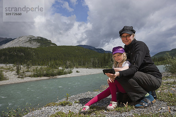 Mutter und Tochter machen ein Selfie am Ufer des Toad River  Muncho Lake Provincial Park  British Columbia  Kanada  Sommer