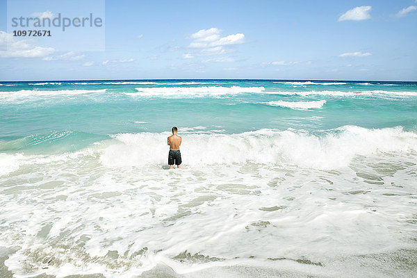 Mann  der im Meer steht  während sich die Wellen am Ufer brechen; Varadero  Kuba