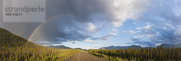Panorama eines doppelten Regenbogens und Regenwolken über einem unbefestigten Abschnitt des Alaska Highway in der Nähe des Kluane Lake  Yukon Territory  Kanada