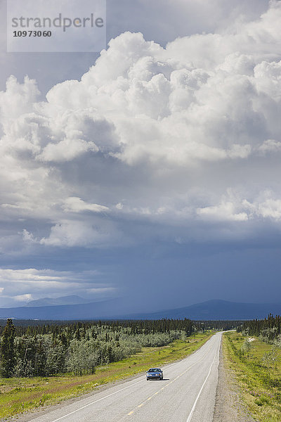 Auto auf dem Alaska Highway mit Regenwolken im Hintergrund  Yukon Territory  Kanada  Sommer