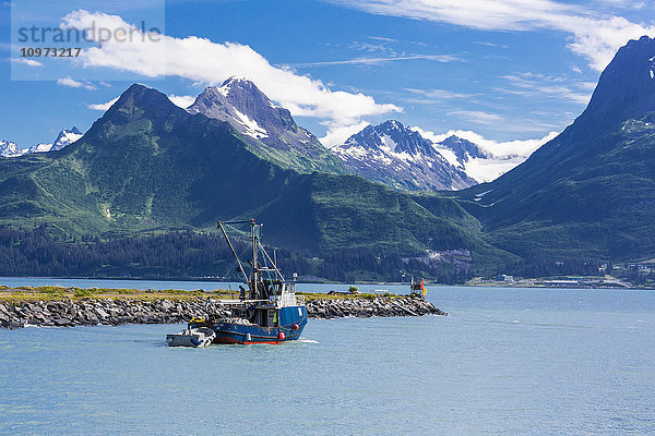 Blick auf ein Wadenfischerboot beim Verlassen des Bootshafens von Valdez und die Chugach Mountain Range  Süd-Zentral-Alaska  Sommer.