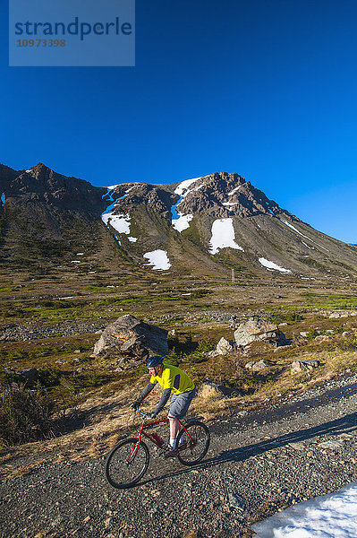 Ein Mann fährt an einem sonnigen Sommertag im Powerline Pass Valley im Chugach State Park in Southcentral Alaska mit dem Fahrrad.