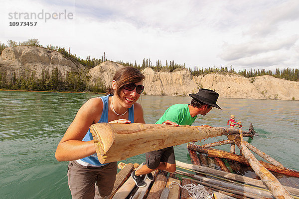 Zwei Personen steuern ein handgefertigtes Floß auf dem Yukon River in der Nähe von Carmacks  Yukon Territory  Kanada