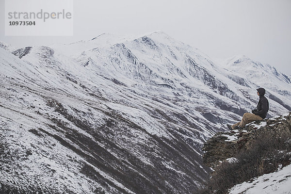 Junger Mann auf einer Klippe mit Blick auf ein arktisches Tal  arktisches Alaska  Spätherbst