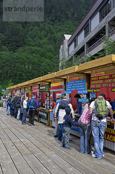 Touristen stehen an den Ständen von elf Reiseveranstaltern an der Anlegestelle für Kreuzfahrtschiffe Schlange  Juneau  Südost-Alaska  Sommer