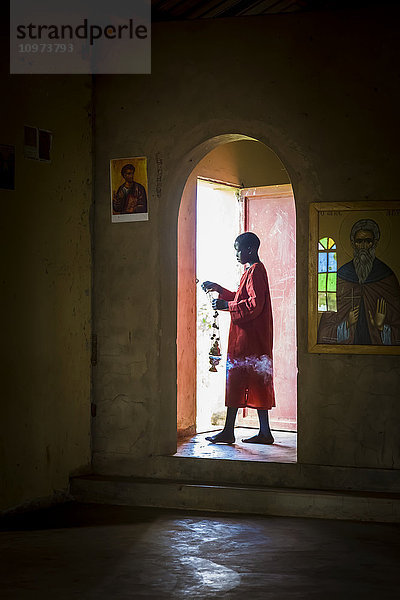 Ein Junge geht durch einen beleuchteten Eingang einer orthodoxen Kirche; Gulu  Uganda