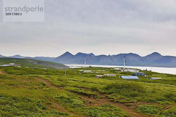 Gebäude und Straßenbeleuchtung von Sand Point mit King Cove und Unga Island Mountains im Hintergrund  Südwest-Alaska  USA  Sommer'.