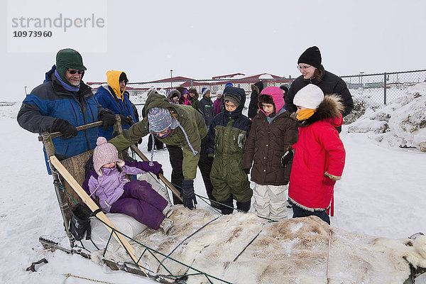 Grundschulkinder in Winterkleidung warten darauf  mit einem Schlitten um die Lagune zu fahren  Barrow  North Slope  Arctic Alaska  USA  Winter'