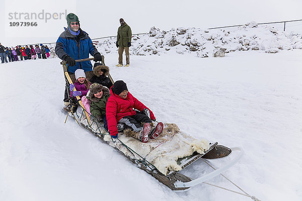 Grundschulkinder fahren auf einem von Schlittenhunden gezogenen Schlitten um die Lagune  Barrow  North Slope  Arctic Alaska  USA  Winter'.