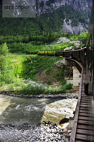 Die Elektrolok der White Pass Railroad zieht die Personenwagen des Zuges über die Bockbrücke  Skagway  Südost-Alaska