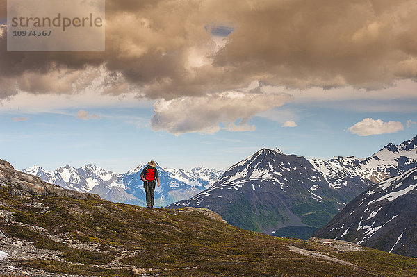 Ein Mann wandert in der Nähe des Harding Icefield Trail mit den Chugach Mountains und dem Resurrection Valley im Hintergrund  Kenai Fjords National Park  Southcentral Alaska