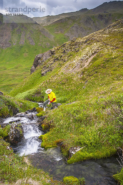 Ein Mann füllt seine Wasserflasche im Hanging Valley in South Fork in der Nähe von Eagle River an einem Sommertag in Süd-Zentral-Alaska.