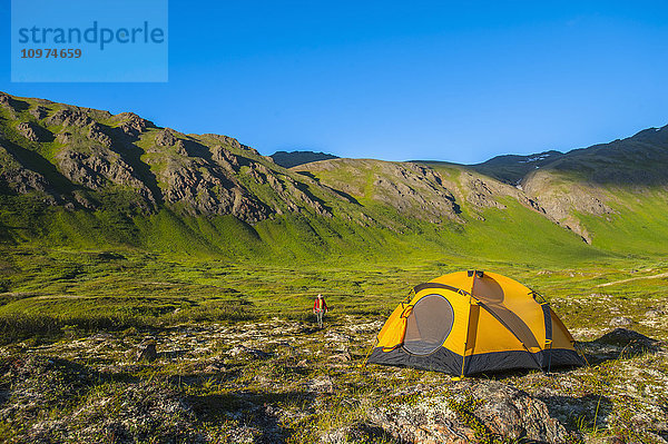 Ein Mann auf seinem Campingplatz im Hanging Valley in South Fork bei Eagle River an einem Sommertag in Süd-Zentral-Alaska.