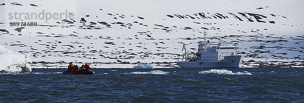 Touristen auf einem Schlauchboot und ein Schiff im Wasser; Spitzbergen  Svalbard  Norwegen'.