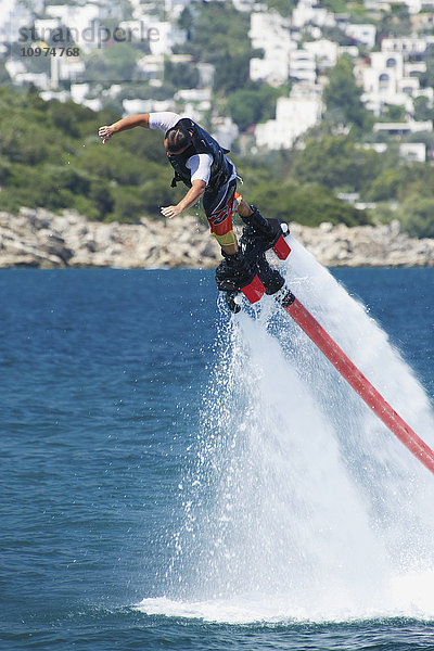 Flyboarder  der aus großer Höhe ins Wasser springt; Torba  Provinz Mugla  Türkei'.