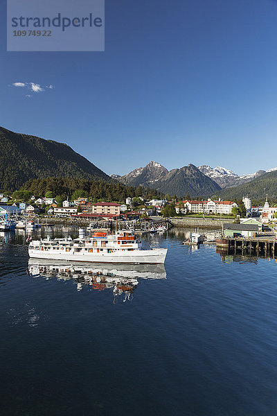 Ein Passagierschiff verlässt den Hafen von Sitka mit Sitka und den Three Sisters Mountains im Hintergrund  Südost-Alaska  USA  Sommer