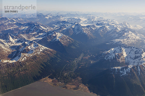 Luftaufnahme von schneebedeckten Gipfeln in den Chugach Mountains mit Girdwood im Vordergrund  Southcentral Alaska  USA  Sommer