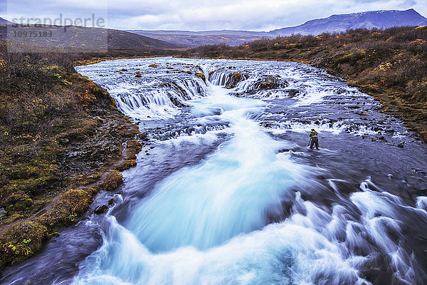 Mann beim Fotografieren des Wasserfalls Bruarfoss; Island