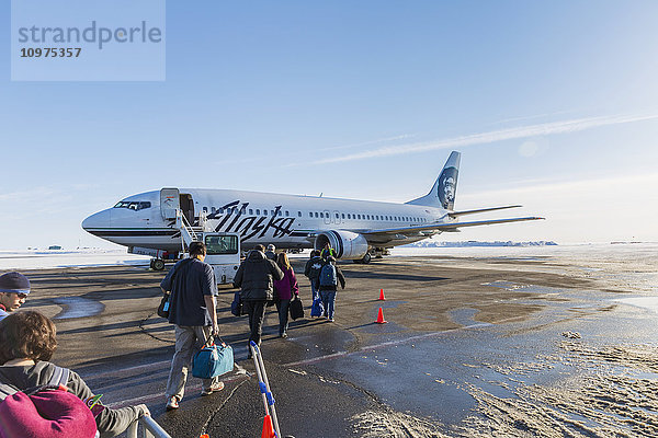 Passagiere gehen auf der Rollbahn zu einem Alaska Airlines 737 Jet in Barrow  Arktis Alaska  USA  Winter