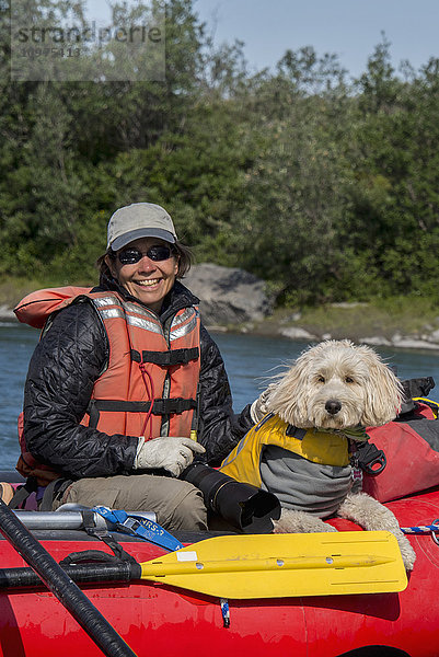 Frau und ihr Golden Doodle sitzen in einem Floß im Sonnenschein auf der Marsh Fork des Canning River im Arctic National Wildlife Refuge  Sommer  Alaska