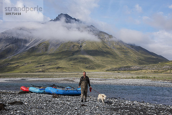 Ein Mann geht mit seinem Hund am Marsh Fork des Canning River im Arctic National Wildlife Refuge spazieren  Sommer  Alaska