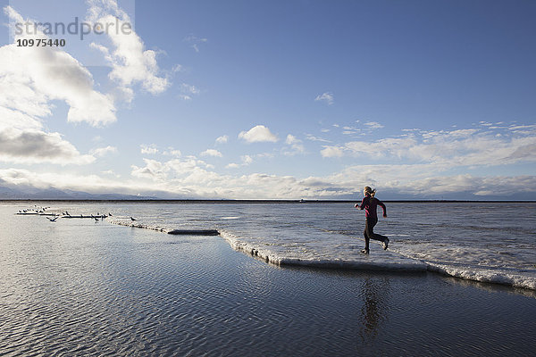 Frau läuft auf dem eisbedeckten Strand in Homer  Kenai-Halbinsel  Süd-Zentral-Alaska