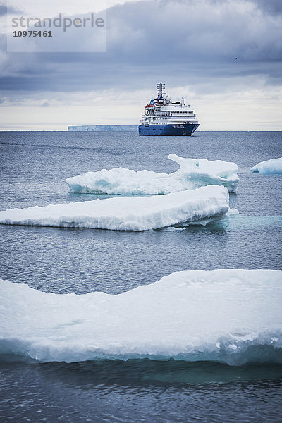 Kreuzfahrtschiff vor Anker mit Eisbergen im Vordergrund; Antarktis'.