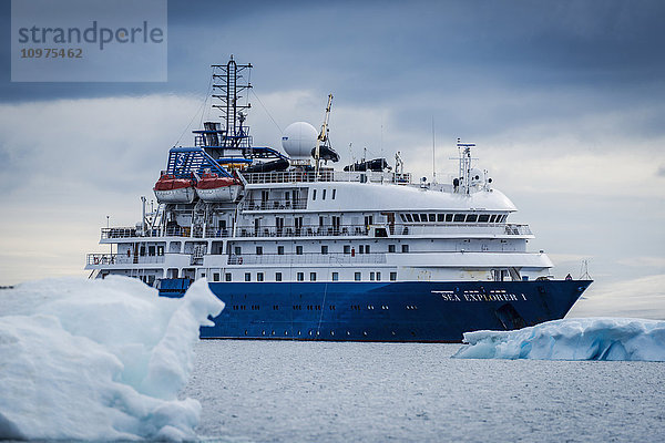 Kreuzfahrtschiff vor Anker zwischen blauen Eisbergen; Antarktis'.