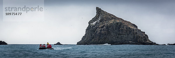 Schlauchboot steuert auf zerklüfteten Felsen im Meer zu; Antarktis .