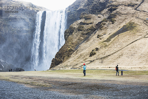 Touristen besuchen den Wasserfall Seljalandsfoss; Island'.
